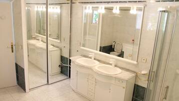 Une salle de bain avec deux lavabos, un grand miroir et une douche.