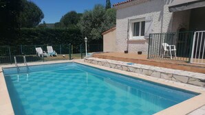 A swimming pool with a checkered pattern, surrounded by stone tiles and a stone deck.