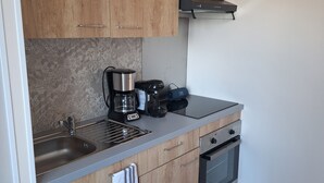 Et moderne køkken med træskabe, en rustfri stålvask, kaffemaskine, elkedel og ovn.