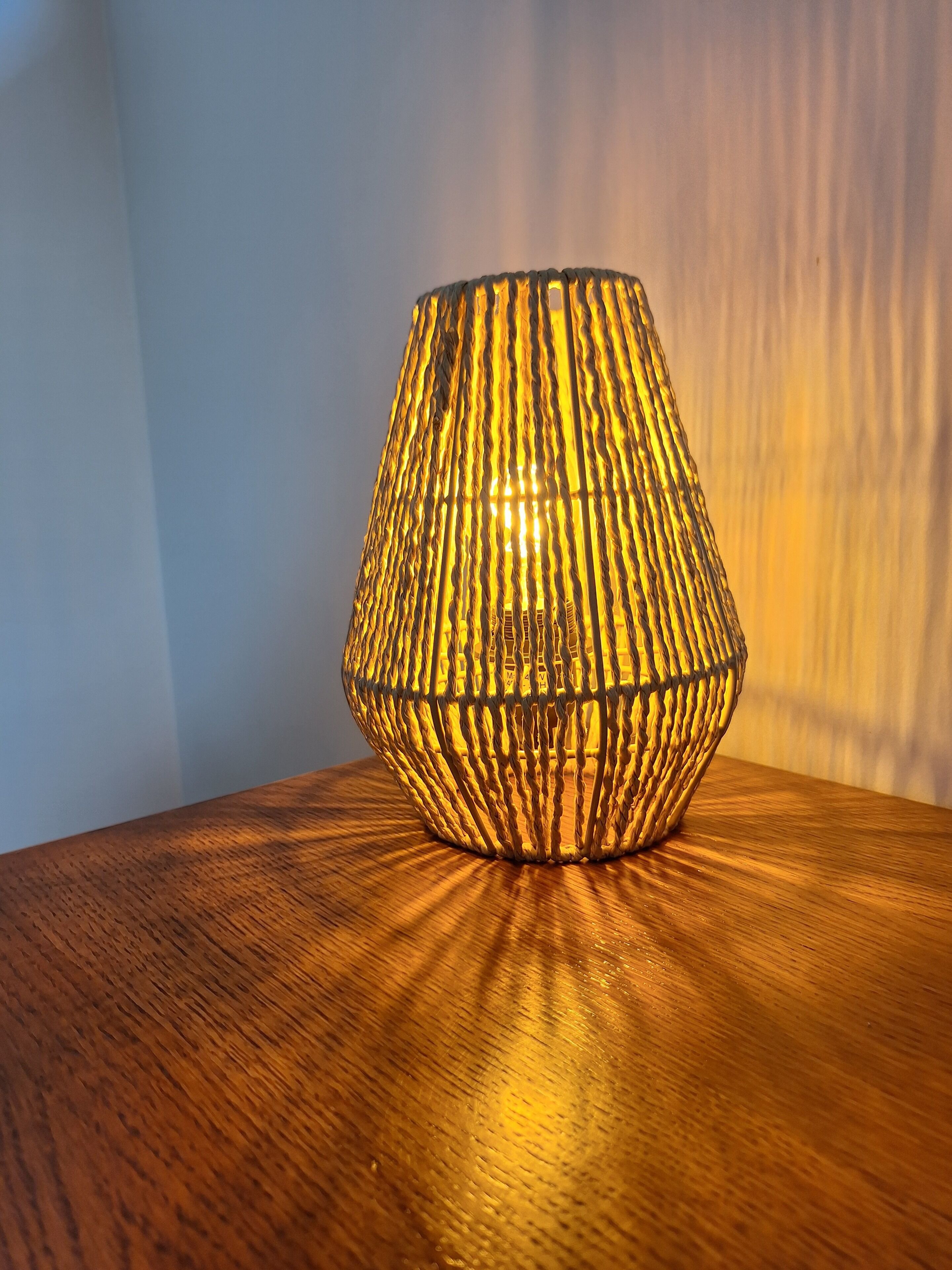 A textured, cylindrical lamp with a warm glow on a wooden surface.