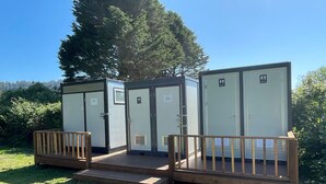 Verplaatsbare toiletten met een houten terras en een bordje met daarop herentoilet en damestoilet.