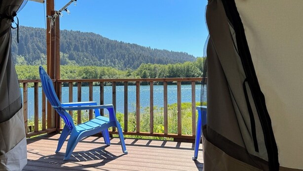 Une terrasse couverte avec vue sur un lac et une forêt.