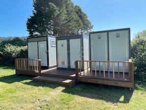 Portable toilets with a wooden deck and a sign indicating a men's and women's restroom.