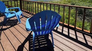 Une terrasse en bois avec des chaises bleues, un auvent et une vue sur un lac et une forêt.
