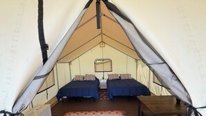 Une pièce aménagée comme une tente, avec deux lits, une table et un tapis orné d’un motif représentant une montagne et un ours.