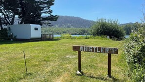 Zona verde con un cartel que dice 'WHISTLER POOL' y una caravana blanca al fondo.