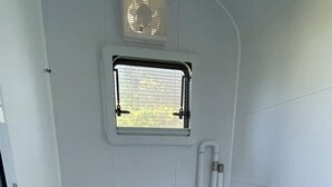 Un baño pequeño con inodoro, ventana y barandilla.