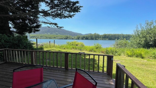 Terraza de madera con vista a un lago y montañas.