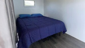 Un dormitorio con una cama, una ventana y una lámpara en el techo.