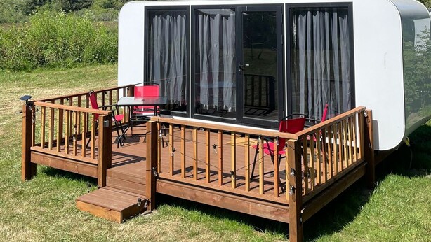 Une caravane équipée d’une terrasse, d’une table et de chaises.
