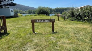 Un panneau indicateur portant l’inscription « BLACKCOMB POOL », placé dans une zone herbeuse, avec un lac et des arbres en arrière-plan.