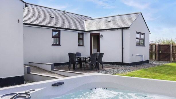 A spa area with a hot tub, outdoor seating, and a small garden. - 3 bedroom accommodation in Rhostrehwfa Nr Llangefni (Rhostrehwfa Nr Llangefni)