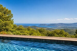 Ein Schwimmbad mit Blick auf das Meer und die Berge.
