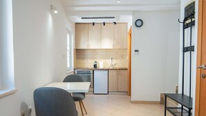 A compact kitchen with a dining area, a small refrigerator, and a clock on the wall. - Casa Campana (Kotor)