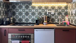 A kitchen with wooden cabinets, a tiled backsplash, a coffee maker, a kettle, and a dishwasher. - Casa Campana (Kotor)