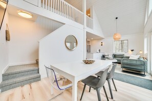 Stylish living space with a white staircase, dining area, and cozy seating area.