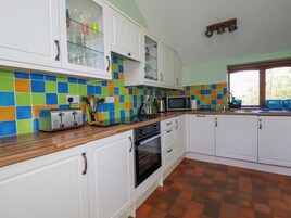 Una cocina con armarios blancos, microondas, tostadora y una ventana con persianas.