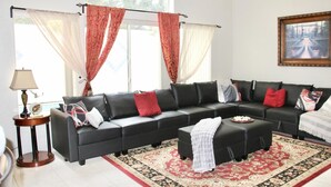 A living room with a sectional sofa, a coffee table, a lamp, and a large window with curtains. - Beautiful home, near the Monterey Bay, Carmel & Pebble Beach (Salinas)