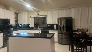 A spacious kitchen with white cabinets, a large island, stainless steel appliances, and a dining area with a table and chairs. - Beautiful home, near the Monterey Bay, Carmel & Pebble Beach (Salinas)