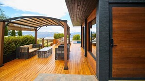Una terraza de madera con mobiliario exterior, una pérgola y vistas a las montañas.