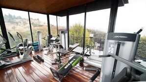 Un gimnasio con diversos equipos de ejercicio, incluyendo una cinta de correr, máquinas de pesas y una banca.