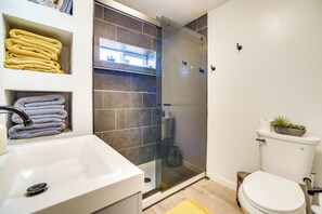 Un bagno moderno con doccia vetrata, lavandino bianco e water.