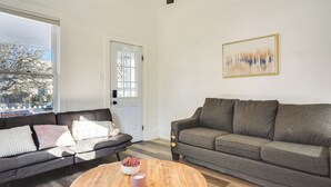 A living room with two sofas, a coffee table, and a door with a window view. - Near UNM & ABQ BioPark: East Dtwn Studio (Albuquerque)