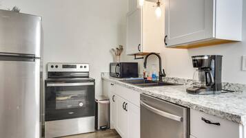 A modern kitchen with stainless steel appliances, a granite countertop, and pendant lighting.