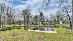 A lakeside property with a dock, boats, and a small house. - Waterfront Home w/ Boat Slips in Northern Michigan (Gladwin)