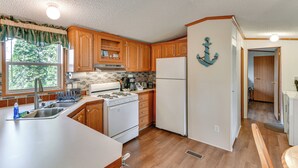 A kitchen with wooden cabinets, a white stove, and a refrigerator. - Waterfront Home w/ Boat Slips in Northern Michigan (Gladwin)