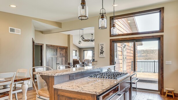 A spacious kitchen with a large island, wooden cabinets, and a view to the outside. - Riverfront Home w/ Yard Games in Wabasha! (Wabasha)