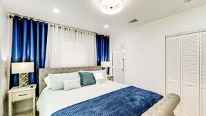 A neatly arranged bedroom with a bed, bedside tables, a nightstand, a bench, and a wardrobe. - 5 Mi to Dtwn: Dallas Home w/ Patio & Fire Pit! (Dallas)