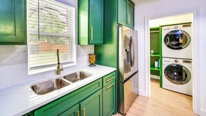 A kitchen with green cabinets, a stainless steel sink, and a built-in washer and dryer. - 5 Mi to Dtwn: Dallas Home w/ Patio & Fire Pit! (Dallas)