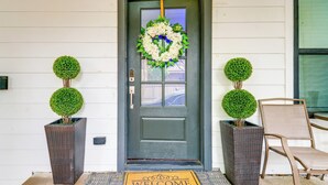 A front door with a wreath, two potted topiary trees, and a chair. - 5 Mi to Dtwn: Dallas Home w/ Patio & Fire Pit! (Dallas)