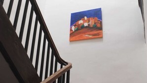 Una escalera con barandilla de madera y una pequeña mesa de madera con un vaso encima.