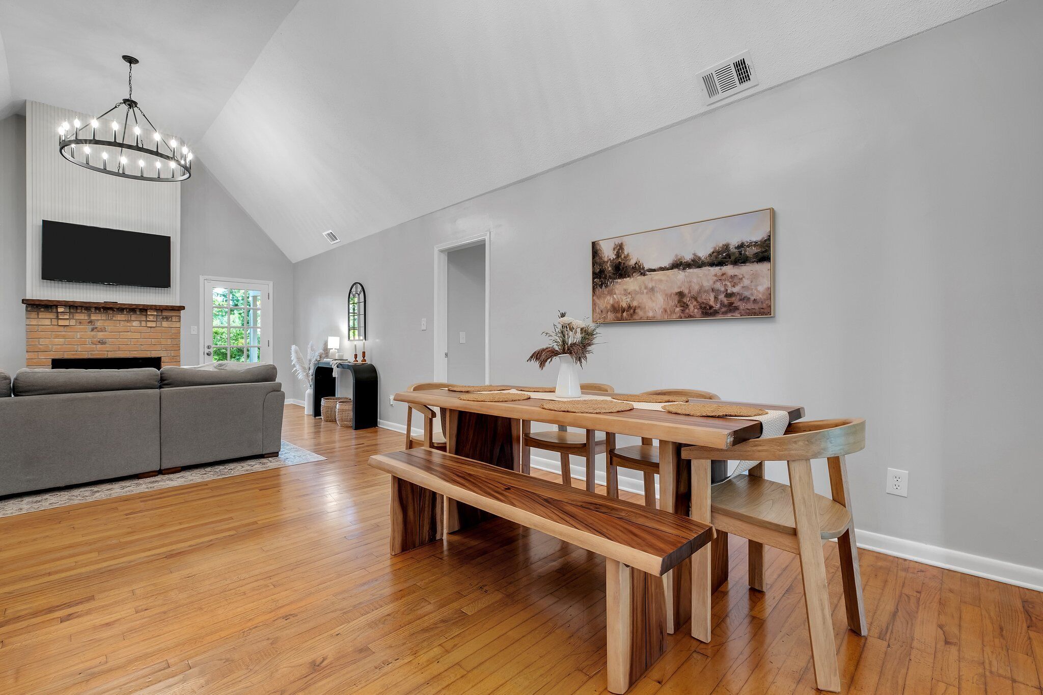 A modern living room with a dining area, hardwood floors, and a fireplace.