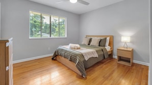 Un dormitorio con cama, mesita de noche, ventilador de techo y ventana con persianas.