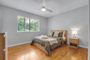A bedroom with a bed, a nightstand, a ceiling fan, and a window with blinds.