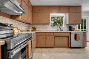 Una cocina moderna con electrodomésticos de acero inoxidable, armarios de madera y un ventanal que proporciona luz natural.