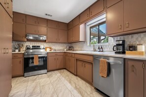 A kitchen with brown cabinets, a stainless steel stove, and a dishwasher.