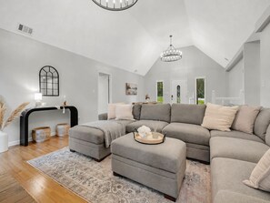 A modern living room with a sectional sofa, ottoman, and a decorative tray.