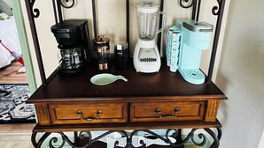 A wooden cabinet with a black metal frame, containing a coffee maker, a blender, and a kettle. - Coeur d' Lovely (Coeur d'Alene)