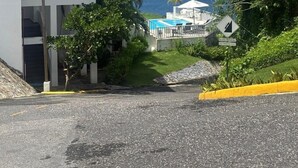Un immeuble de deux étages doté d’un balcon donnant sur une piscine et la mer.