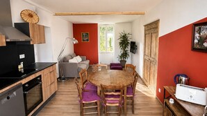 Een compacte keuken met een eethoek, houten kastjes, een inbouwoven en een eettafel met stoelen.