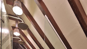 Een klein, afgesloten balkon met betegelde vloer, een houten bankje en een hangende lamp.