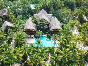 A resort with thatched-roof bungalows, a central pool, and lush tropical vegetation. - Cayena by Masaya Collection (Santa Marta)
