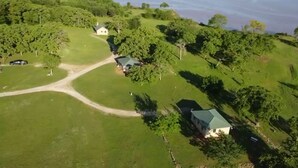 Luchtbeeld van een bezit met meerdere gebouwen, een onverharde weg en omliggend groen.