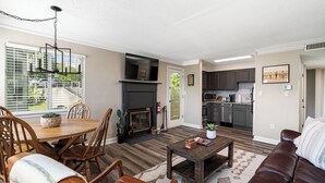 A spacious living room with a fireplace, dining area, and kitchen.