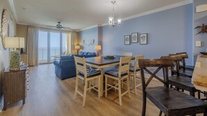 Un coin repas avec une table et des chaises en bois, un ventilateur de plafond et une vue sur le balcon.
