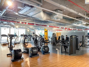 Uma academia com esteiras, elípticos e máquinas de musculação.